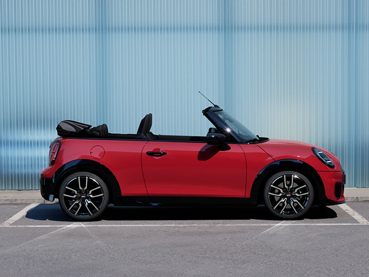 Side view of the MINI Cooper Convertible in Chili Red on a street.